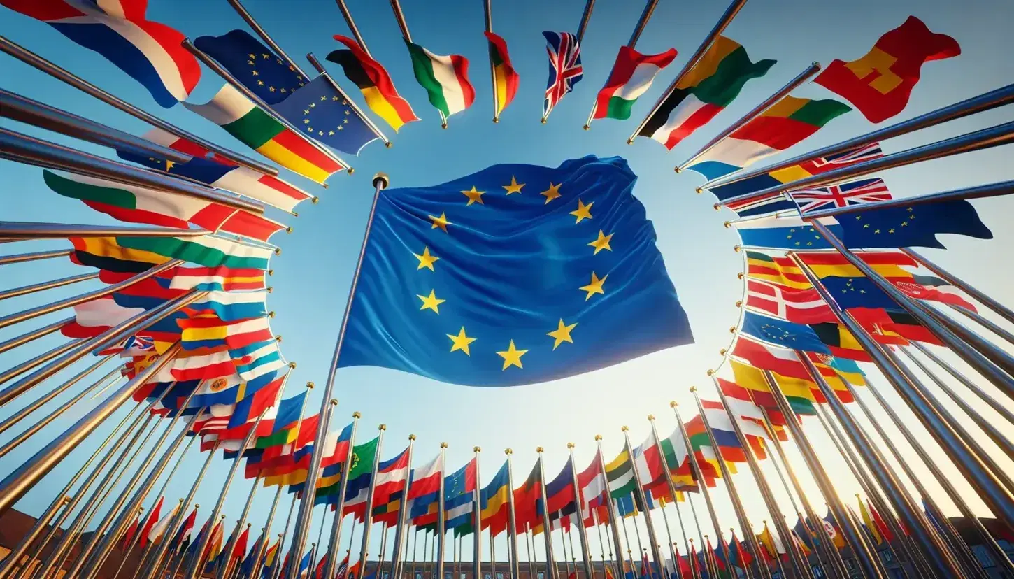 Bandiere nazionali dei paesi dell'Unione Europea disposte in cerchio con al centro la bandiera UE su sfondo cielo azzurro.