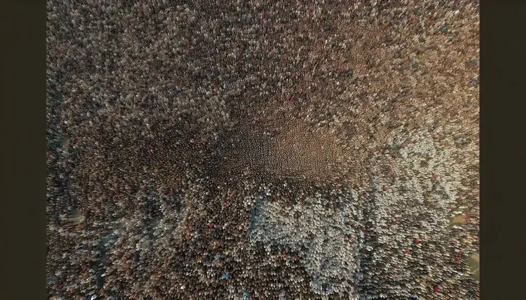 Folla densa vista dall'alto con abiti colorati e percorso irregolare vuoto al centro, illuminazione uniforme senza ombre.