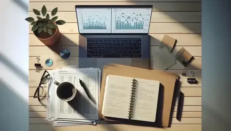 Escritorio de trabajo con papeles, portátil mostrando gráficos, cuaderno abierto con bolígrafo, taza de café humeante, gafas y planta verde bajo luz natural.