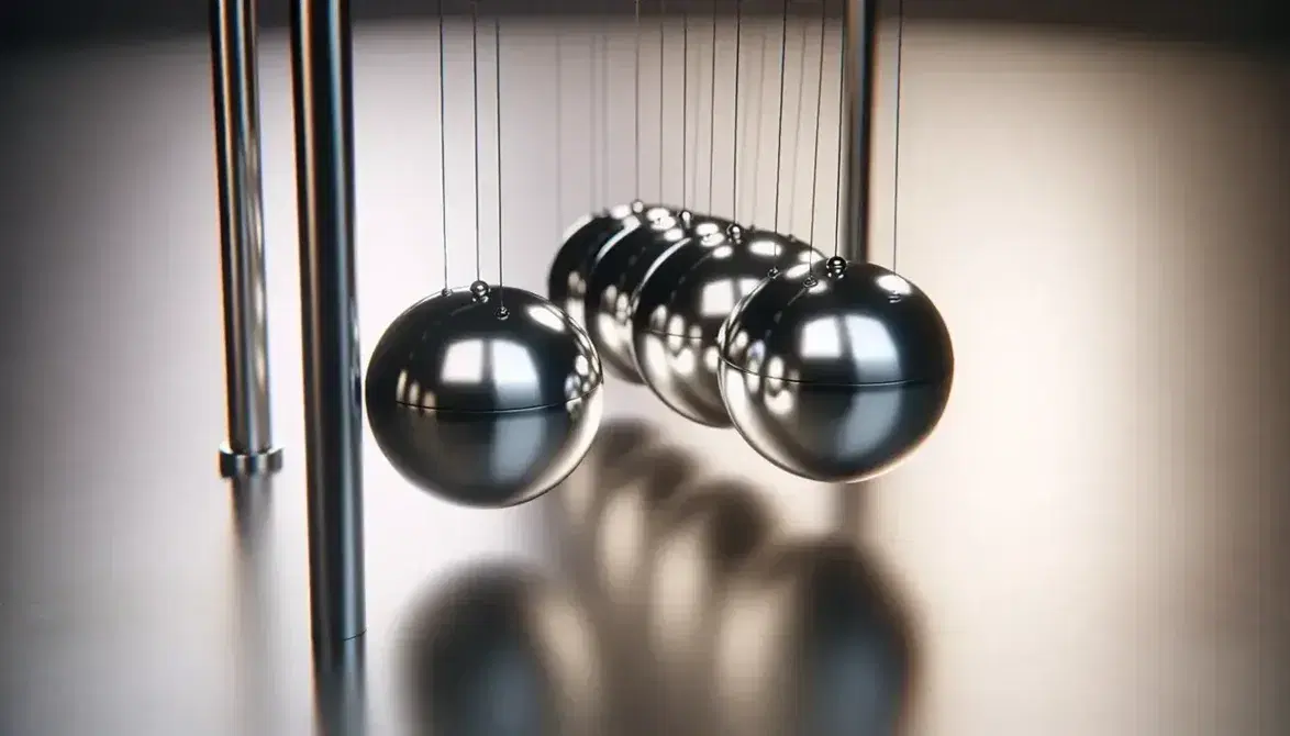 Péndulo de Newton con cinco esferas metálicas alineadas, una elevada a punto de ser soltada, suspendidas de hilos paralelos, con iluminación suave y fondo neutro desenfocado.