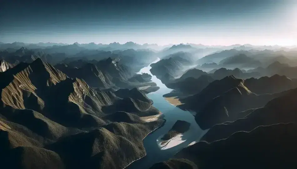 Vista aerea di una catena montuosa con fiume serpeggiante, vegetazione rigogliosa e picchi rocciosi illuminati dal sole.